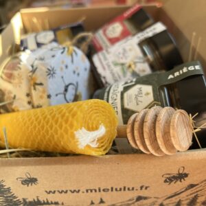 Coffret lulu contenant des produits divers des ruches des pyrénées ariégeoises. Contient du miel, des bougies à la cire d'abeille, des bonbons au miel et une cuillère à miel.